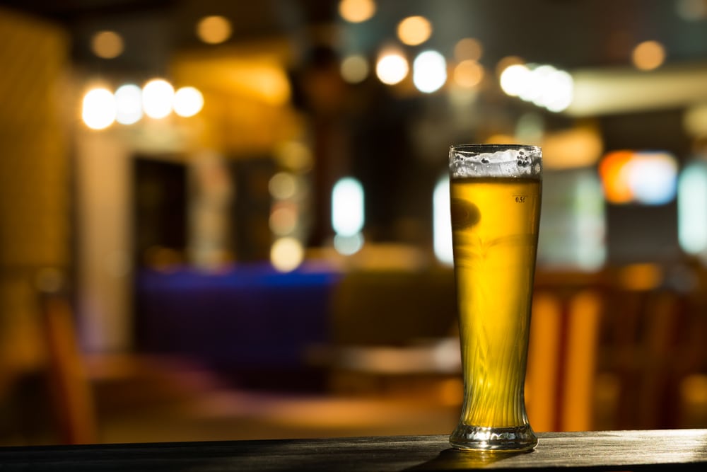 Tall Glass of Beer on Bar Counter with Blurred Background